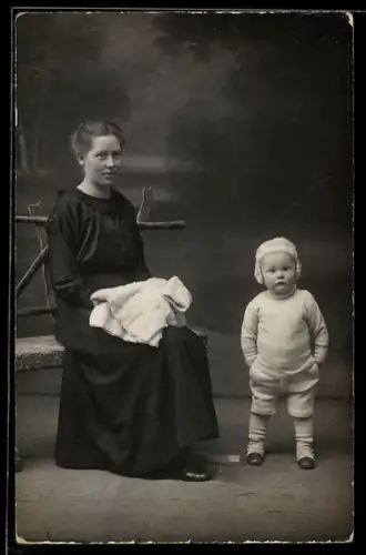 Foto-AK Frau im dunklen Kleid mit Kleinkind, Studiokulisse