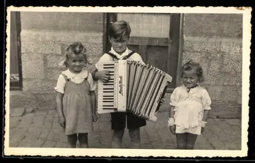 Foto-AK Kleiner Akkordeonspieler mit zwei Mädchen