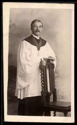 AK Priester an einem Stuhl