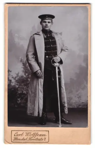 Fotografie Carl Wolffram, Stendal, Breitestr. 7, Husar in Attila mit Mantel, Krätzchen und Säbel