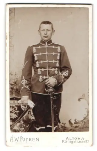 Fotografie A. W. Popken, Altona, Königstrasse 97, Husar in Attila mit Krätzchen und Säbel