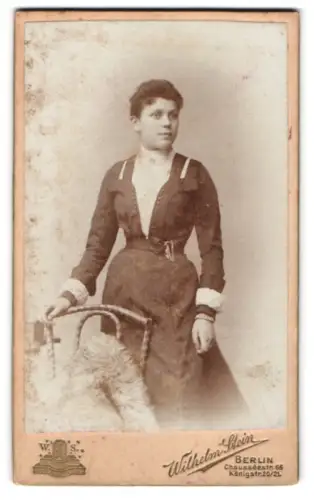 Fotografie Wilhelm Stein, Berlin, Chausseestrasse 66, Frau mit elegantem Kleid neben einem Stuhl
