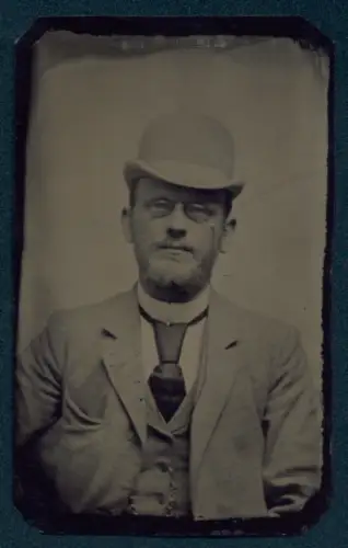 Fotografie Ferrotypie unbekannter Fotograf und Ort, Porträt eines Mannes mit Melone und Brille