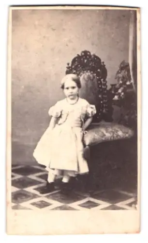 Fotografie A. F. Knoop, Eutin, Mädchen im Kleid neben einem Stuhl