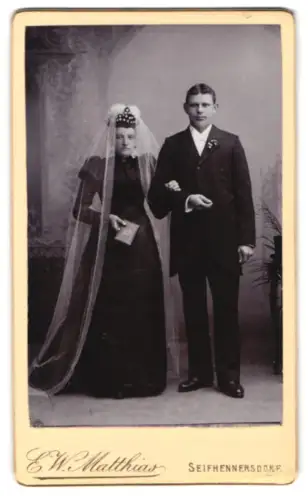 Fotografie E. W. Matthias, Seifhennersdorf, Hochzeitspaar mit Braut in dunklem Kleid im Studio