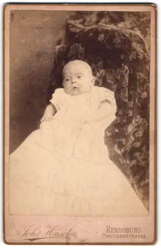 Fotografie Johs. Hüseler, Rendsburg, Prinzessinstrasse, Porträt eines Babys in Taufkleidung