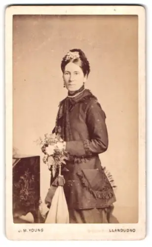 Fotografie J. M. Young, Llandudno /North Wales, Elegante Dame mit Blumen