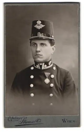 Fotografie Atelier Strauss, Wien, Kohlmarkt 5, k.u.k. Eisenbahnbeamter Augustin Buzek mit Kappe und Jubiläumskreuz 1908
