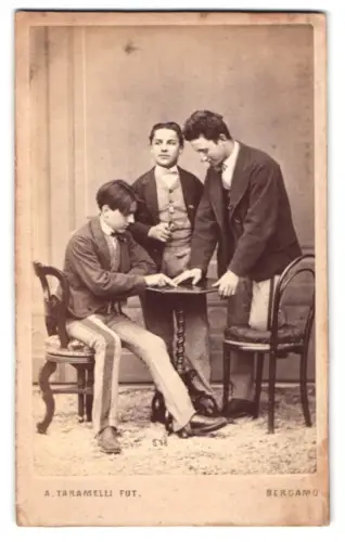 Fotografie Andrewa Taramelli, Bergamo, Gruppenaufnahme drei junge Männer in Anzügen am Tisch