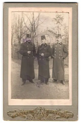 Fotografie unbekannter Fotograf und Ort, drei k.u.k. Offiziere in Mänteln mit Paroli und Kappe, Januar 1906
