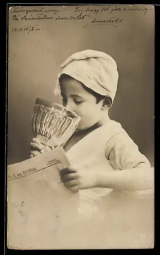 AK Kleiner Junge liest Zeitung und trinkt aus einem riesigen Glas