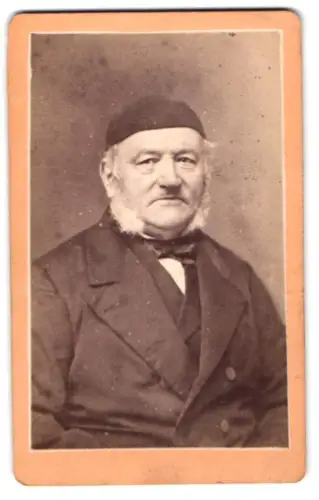 Fotografie J. M. Graack, Kiel, Ecke der Dänischen und Burg-Strasse, Herr im Anzug mit Mütze