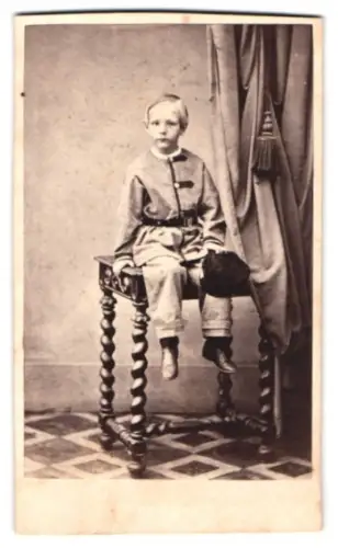 Fotografie A. F. Knoop, Eutin, Junges Kind auf dekorativem Tisch sitzend