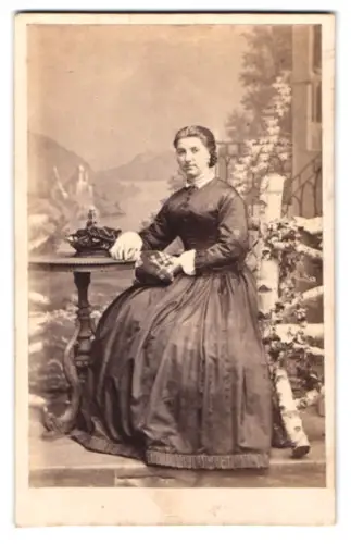 Fotografie A. Mencke & Co., Hamburg, Bleichenbrücke 21, Frau in elegantem Kleid vor Studiokulisse