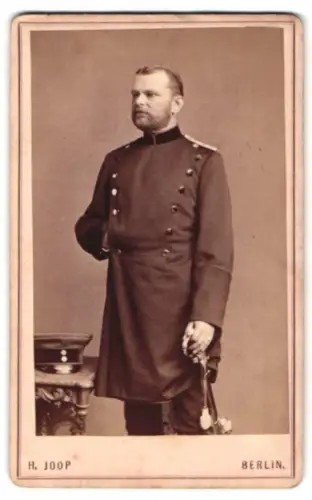 Fotografie H. Joop, Berlin, Unter den Linden 13, Offizier im Überrock mit Schirmmütze und Säbel