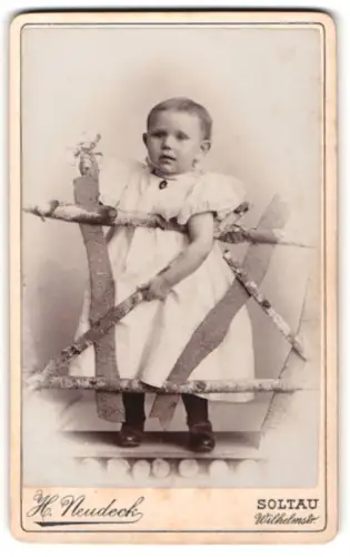 Fotografie H. Neudeck, Soltau, Wilhelmstrasse, Kleinkind hinter rustikalem Holzzaun