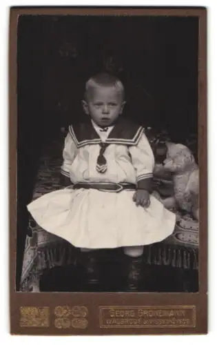 Fotografie Georg Gronemann, Walsrode, Kleinkind in Matrosenkleid mit Teddybär