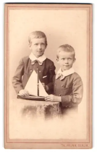Fotografie Th. Prümm, Berlin, Unter den Linden 51, Zwei Jungen mit Segelboot-Spielzeug