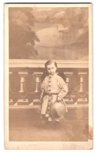 Fotografie unbekannter Fotograf und Ort, Kind mit Strohhut vor gemalter Kulisse