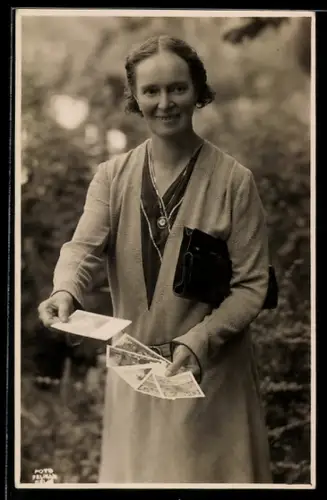 AK Lächelnde Frau mit Ansichtskarten in den Händen