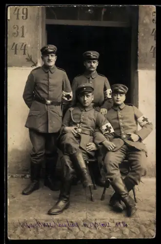 Foto-AK Vier Sanitäter in Uniform mit Armbinde Rotes Kreuz vor einem Hauseingang