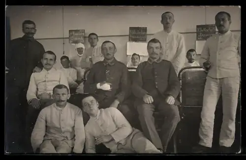 Foto-AK Patienten im Lazarett, Tafeln mit Angaben zur Verwundung, Gruppenbild, Rotes Kreuz