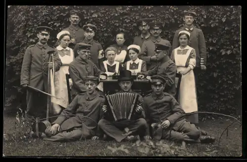 Foto-AK Soldatengruppe mit Rotkreuz-Krankenschwestern und Akkordeon im Freien