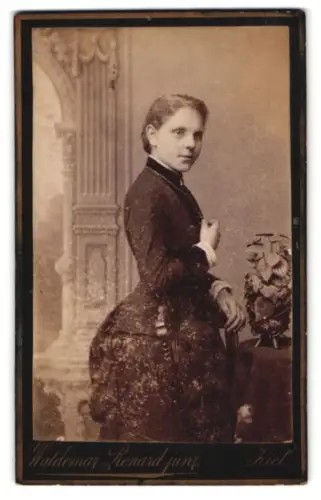 Fotografie Waldemar Renard jun., Kiel, Sophienblatt 18, Frau im Kleid vor dekorativem Hintergrund