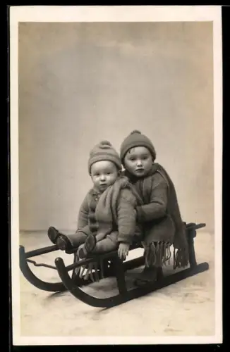 Foto-AK Zwei kleine Kinder in Winterkleidung auf einem Schlitten
