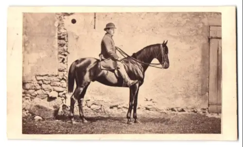 Fotografie unbekannter Fotograf und Ort, Mann auf Pferd vor einer Hauswand