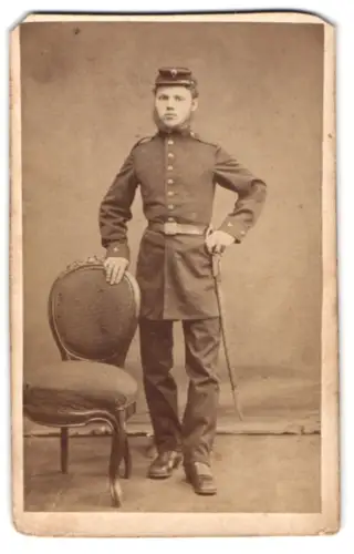 Fotografie J. Leehr, Riga, gr. Schmiede & Kalk-Str. Ecke, Soldat in Uniform mit Schirmmütze und Seitenwaffe