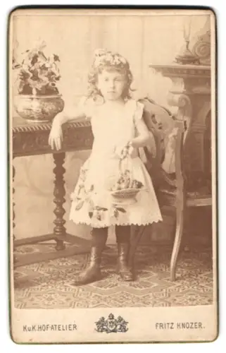 Fotografie Fritz Knozer, Wien, Mayerhofgasse 8, Blumenmädchen mit Blumenkorb an einem Tisch lehnend