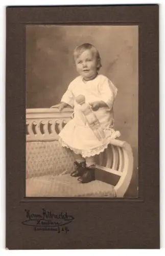 Fotografie Herm. Albrecht, Hamburg, Steindamm 29, Kind mit Puppe auf einer Bank stehend