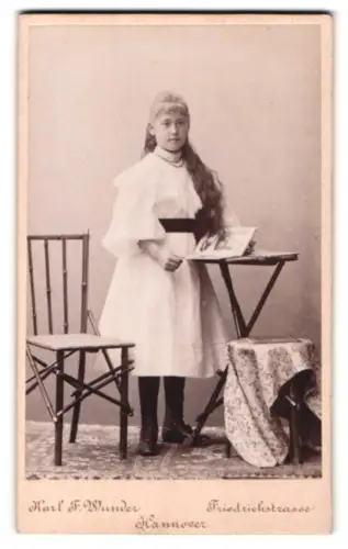Fotografie Karl F. Wunder, Hannover, Friedrichstrasse, Mädchen mit langem Haar mit Buch am Tisch