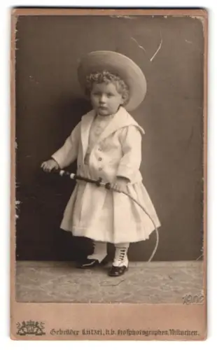 Fotografie Gebrüder Lützel, München, Kleiner Junge im Kleid mit Peitsche