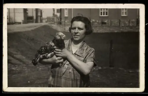 Foto-AK Frau mit Vogel in den Händen vor einem Gebäude