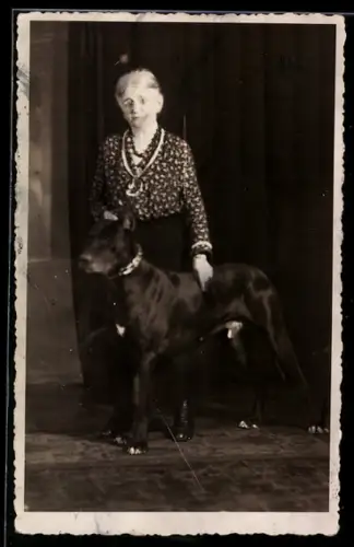 Foto-AK Ältere Dame mit grossem Hund vor einem Vorhang