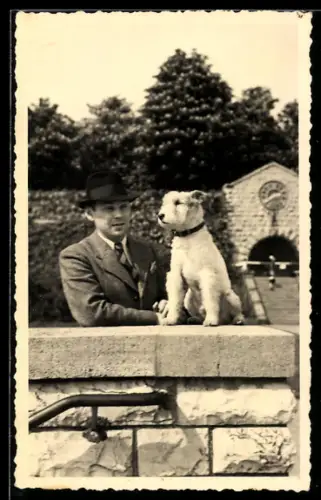 Foto-AK Herr mit Terrier auf einer Mauer im Sonnenschein