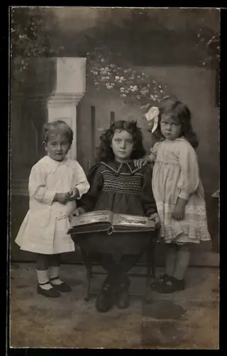 Foto-AK Drei Kinder mit einem Fotoalbum, Ansichtskartengeschichte