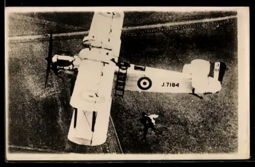 Foto-AK Britischer Militär-Doppeldecker mit Kennung J-7184 im Fluge, Fallschirmspringer bei Absprung