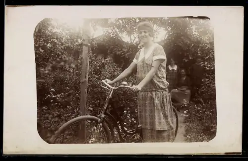 Foto-AK Frau mit Fahrrad in einem Garten