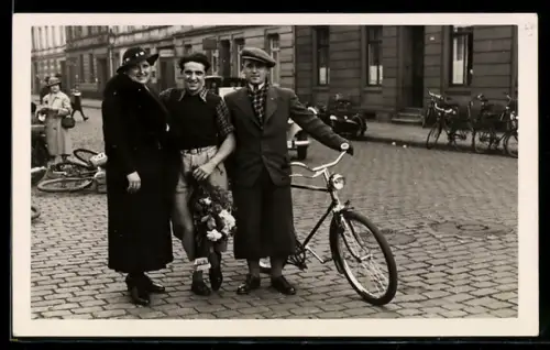 Foto-AK Mann mit Fahrrad auf gepflasterter Strasse, im Hintergrund Motorrad