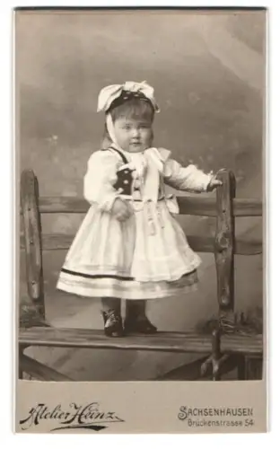 Fotografie Atelier Heinz, Frankfurt am Main, Brückenstrasse 54, Kind in deutscher Tracht auf Holzbank
