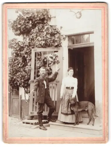 Fotografie unbekannter Fotograf und Ort, Mann und Frau mit Hund vor einer Tür