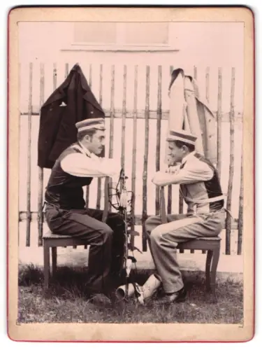 Fotografie unbekannter Fotograf und Ort, Studenten Max Mausser und Freund mit Tellermützen auf Stühlen sitzend 1895