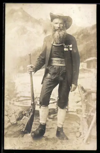 Foto-AK Mann mit Orden und Gewehr vor der Kulisse eines Gebirgspanoramas