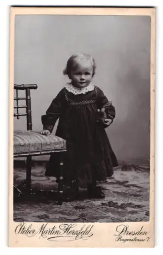 Fotografie Atelier Martin Herzfeld, Dresden, Pragerstrasse 7, Kleinkind steht neben Stuhl