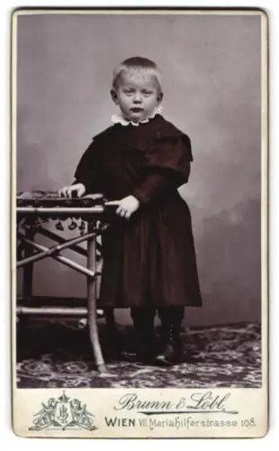 Fotografie Brunn & Löbl, Wien, Mariahilferstrasse 108, Kind steht neben Tisch