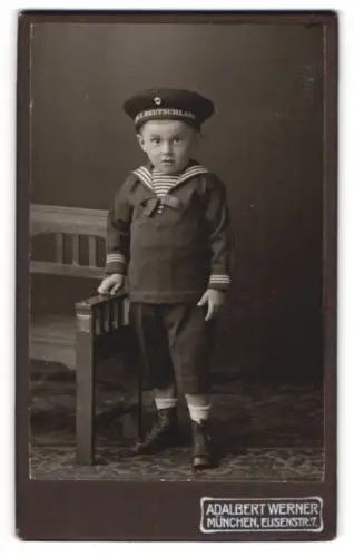 Fotografie Adalbert Werner, München, Elisenstrasse 7, Kind im Matrosenanzug mit Tellermütze, Band S.M.S. Deutschland