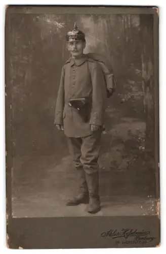 Fotografie Aterlier Hasselmeier, Hamburg, Gr. Bäckerstr. 25, Soldat in Feldgrau Uniform mit Pickelhaube, Pistole